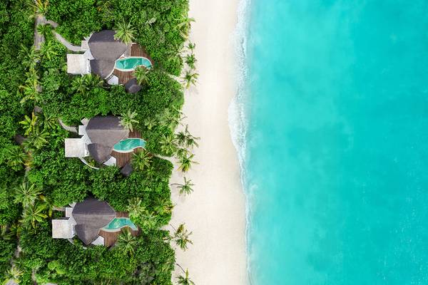 Luftaufnahme des JW Marriott Maldives Resort & Spa mit drei runden Gebäuden am Strand und Infinity-Pools.