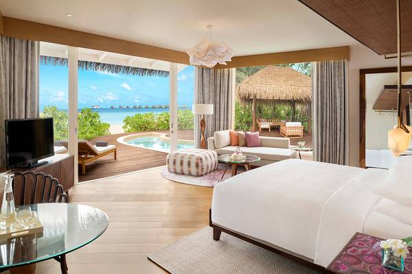 Innenansicht einer Suite im JW Marriott Maldives Resort & Spa mit Blick auf einen Swimmingpool und eine tropische Umgebung.