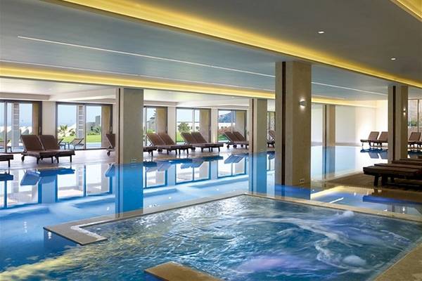 Schwimmbadbereich im Atlantica Imperial Resort & Spa mit Loungestühlen und Panoramafenstern.