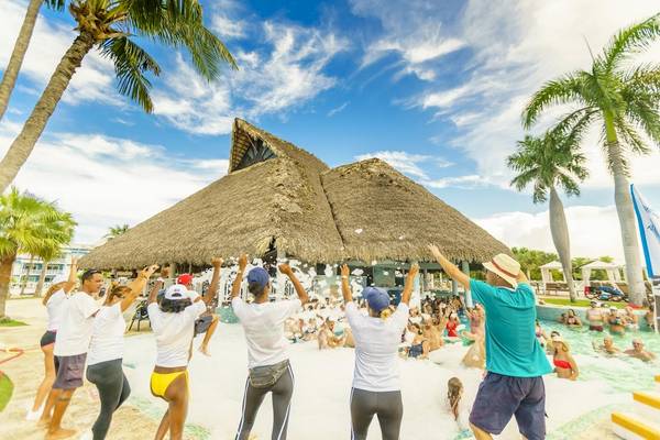 Poolparty im Royalton Hicacos Resort & Spa mit vielen Teilnehmern und Palmen im Hintergrund.