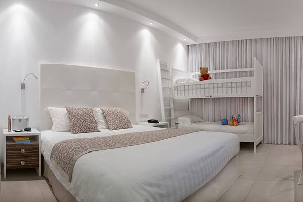 Inneneinrichtung eines Zimmers im Asterias Beach Hotel mit zwei Betten, einem Fernseher, und Spielzeug.