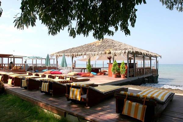 Loungebereich des Ephesia Holiday Beach Clubs am Strand mit Sonnenliegen und einem Sonnenschirm.