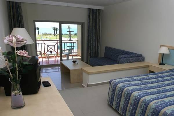 Ein Hotelzimmer im Ephesia Holiday Beach Club mit einem Bett, einer Couch, einem Tisch und einem Balkon mit Meerblick.