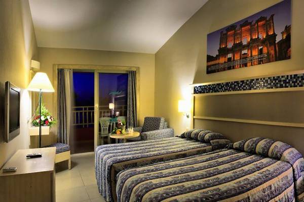 Doppelzimmer im Ephesia Holiday Beach Club mit zwei Betten, Tisch, Fernseher und Balkon.