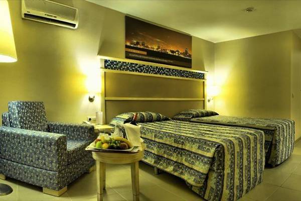Doppelzimmer im Ephesia Holiday Beach Club mit zwei Betten, Tisch, Stuhl und Obstteller.