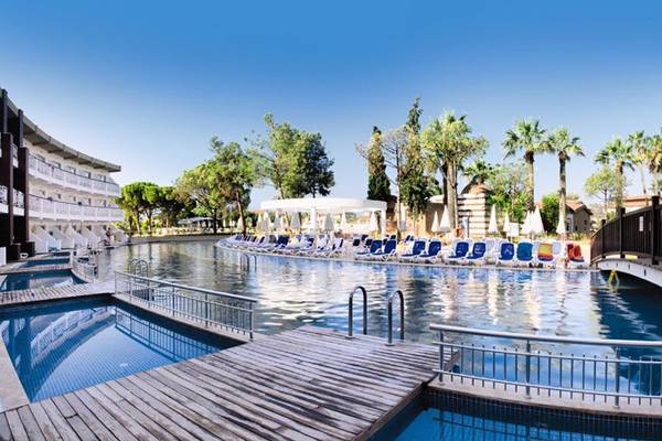 Außenpool des Ephesia Holiday Beach Club Hotels mit Holzsteg und Liegestühlen.