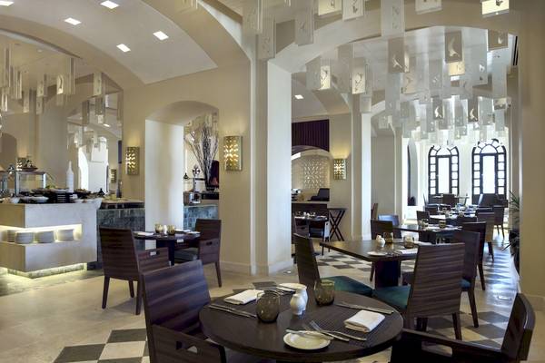 Innenansicht des Restaurants im Salalah Rotana Resort mit runden Tischen und Stühlen.