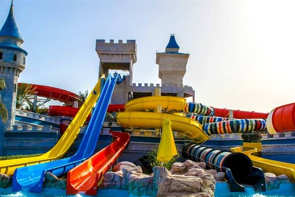 Wasserpark des Serenity Alma Heights Hotels mit bunten Rutschen und Burg im Hintergrund