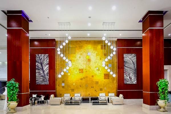 Lobby des Serenity Alma Heights Hotels mit gelber Wand, Kronleuchtern und Möbeln.