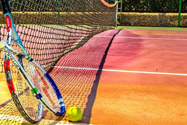 Tennisschläger neben einem Tennisball auf einem Tennisplatz.