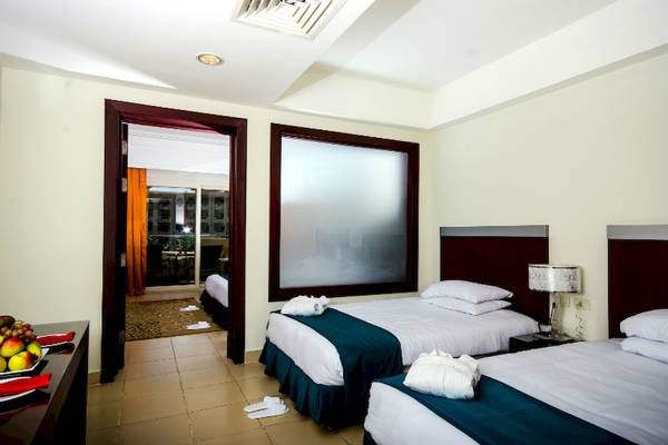 Doppelzimmer im Serenity Alma Heights Hotel mit zwei Betten, frischen Handtüchern und Früchten auf dem Tisch.