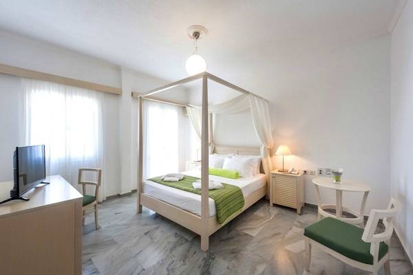 Schlafzimmer im Narges Hotel mit Himmelbett, Fernseher, Schreibtisch und zwei grünen Stühlen.