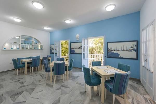 Speiseraum im Narges Hotel mit blauen Stühlen und Tischen, maritimen Gemälden und hellen Wänden.