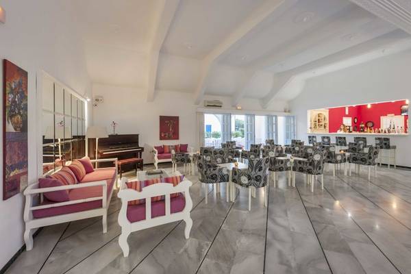 Loungebereich des Narges Hotels mit weißen Möbeln, Klavier und rotem Hintergrund.