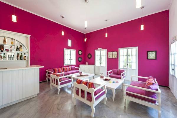 Innenraum des Narges Hotel mit pinken Wänden, weißen Möbeln und einer Bar.