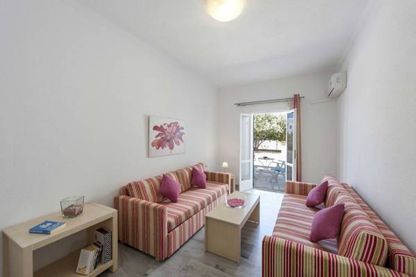 Wohnzimmer des Narges Hotels mit zwei gestreiften Sofas, einem Tisch und einem offenen Fenster.
