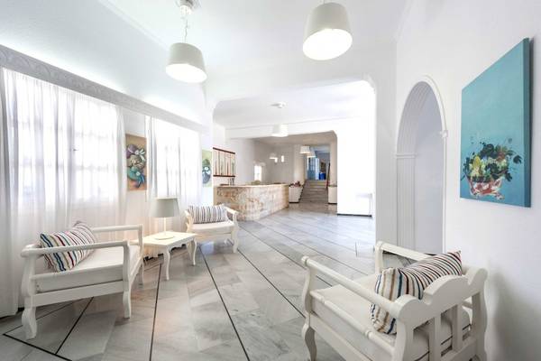 Innenansicht der Lobby des Narges Hotels mit weißen Möbeln, Kunstwerken an der Wand und einer Treppe im Hintergrund.