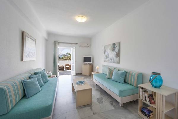 Innenbereich des Narges Hotels mit zwei blauen Sofas, einem Tisch und einem Fernseher neben einer Tür.