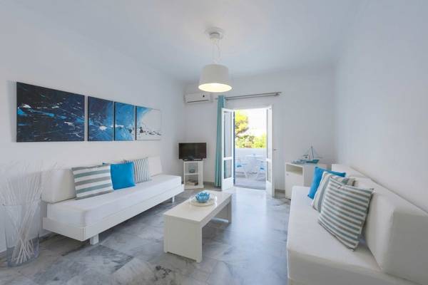 Wohnzimmer des Narges Hotels mit weißen Sofas, einem Tisch und einer offenen Tür.