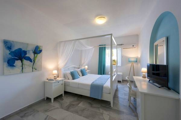 Schlafzimmer im Narges Hotel mit einem weißen Himmelbett, blauen Kissen und Decken, einem Fernseher, und einer Lampe.