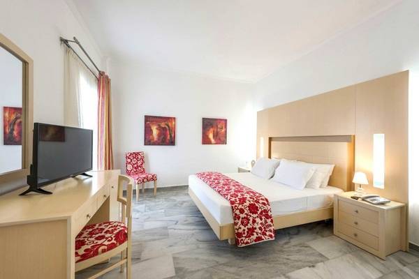 Innenansicht eines Narges Hotel Zimmers mit Bett, Fernseher und Schreibtisch.