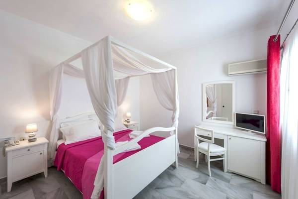 Schlafzimmer im Narges Hotel mit einem vierposterbett, weißem kleiderschrank, schreibtisch und rotem vorhang.