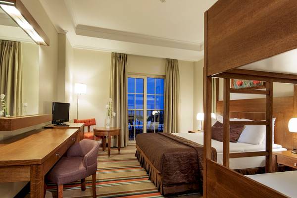 Ein Schlafzimmer im Sunis Elita Beach Resort Hotel mit einem Bett, Schreibtisch und Fenstern.