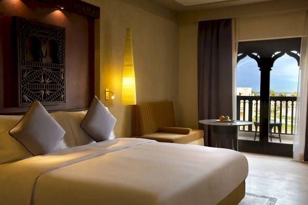 Hotelzimmer im Salalah Rotana Resort mit Bett, Möbeln und Balkon.