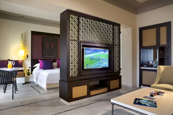 Suite-Interieur im Salalah Rotana Resort mit Fernseher, Bett und Wohnzimmermöbeln.