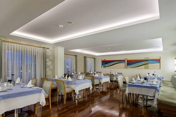 Restaurant im Sunis Elita Beach Resort Hotel mit blauen Tischen und Stühlen auf Holzboden.