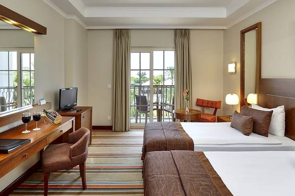Hotelzimmer im Sunis Elita Beach Resort Hotel & Spa mit zwei Betten, Schreibtisch und Balkon.