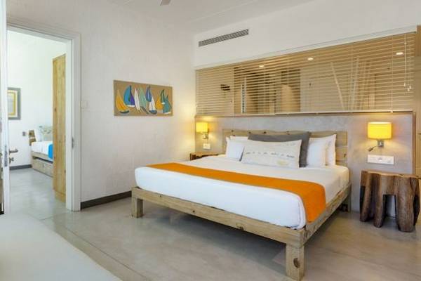 Das elegante Schlafzimmer im Zilwa Attitude Hotel mit einem großen Bett, Holzmöbeln und modernen Kunstwerken.