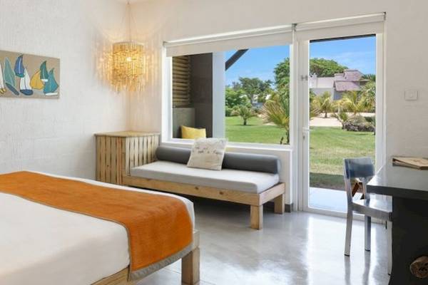 Innenansicht eines Hotelzimmers mit Bett, Tagesbett, Lampe und großem Fenster mit Gartenblick