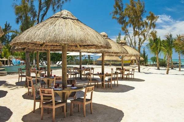 Sitzplatz im Freien des Zilwa Attitude Hotels am Strand mit Palmen und Tischen