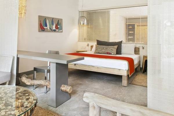 Innenansicht eines Zimmers im Zilwa Attitude Hotel mit einem Bett, einem Tisch, Stühlen und Dekor.