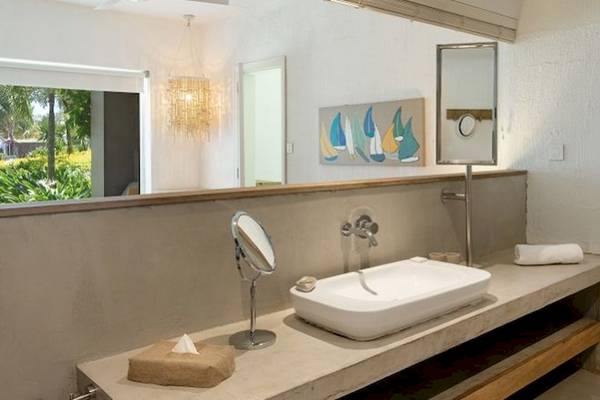 Badezimmer im Zilwa Attitude Hotel mit Spiegel, Waschbecken und Fenster.