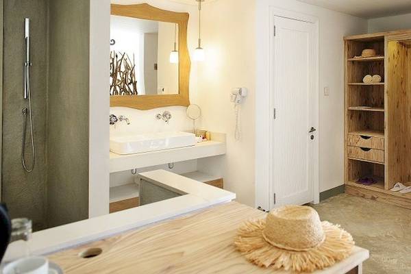 Badezimmer im Zilwa Attitude Hotel mit weißem Waschbecken, Spiegel und Holzschrank.