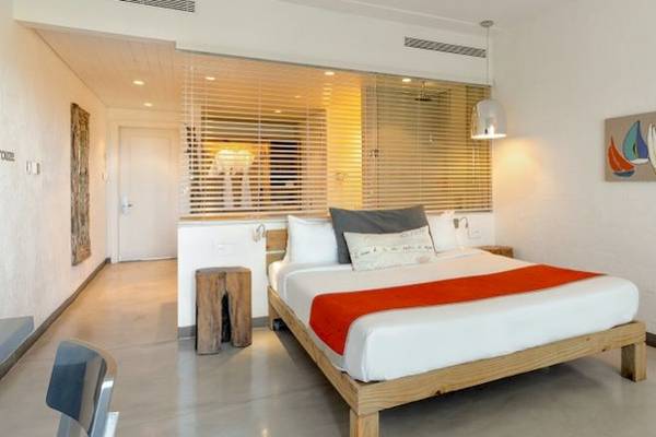 Ein modernes Hotelzimmer im Zilwa Attitude Hotel mit einem Bett, Kissen, Decken und einer Wanddekoration.