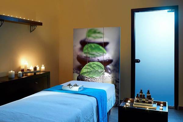 Behandlungsraum im Michelangelo Resort & Spa mit Massageliege, Kerzen und Pflanzendekor.