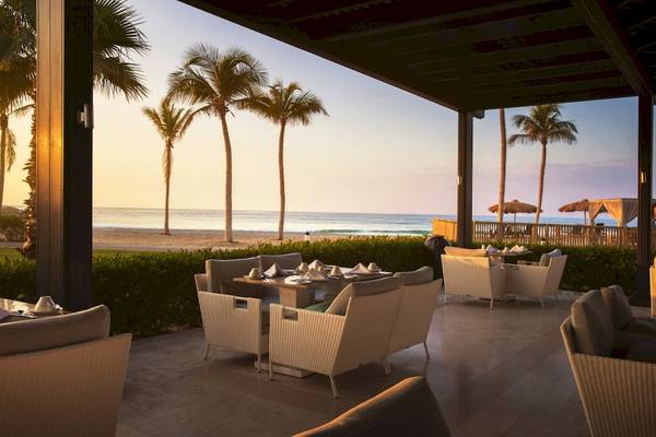 Terrasse des Salalah Rotana Resorts mit Blick auf einen Strand und Palmen