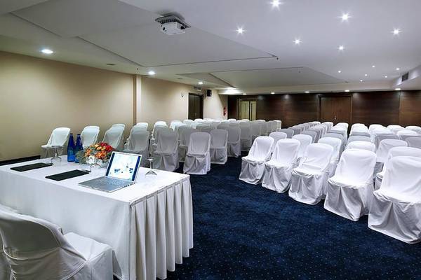 Konferenzraum im Michelangelo Resort & Spa mit gedecktem Tisch, Laptop und gedeckten Stühlen.