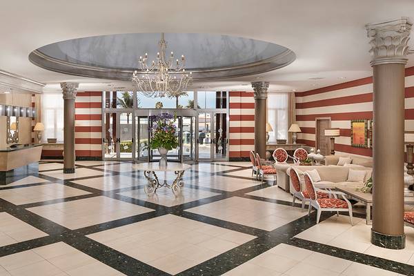 Foyer des HD Parque Cristobal Hotels mit Kronleuchter, schwarzen und weißen Fliesen, roten und weißen Streifen und Möbeln.