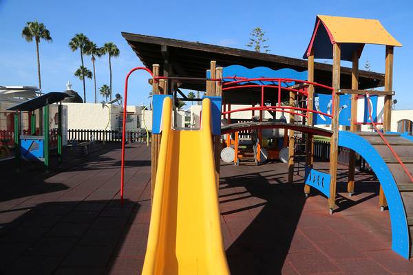 Spielplatz im HD Parque Cristobal mit gelber Rutsche und überdachtem Bereich.