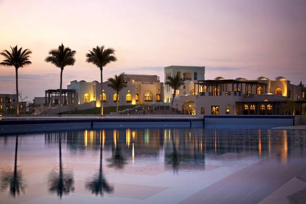 Salalah Rotana Resort Pool bei Sonnenuntergang mit Palmen und Gebäudereflexion