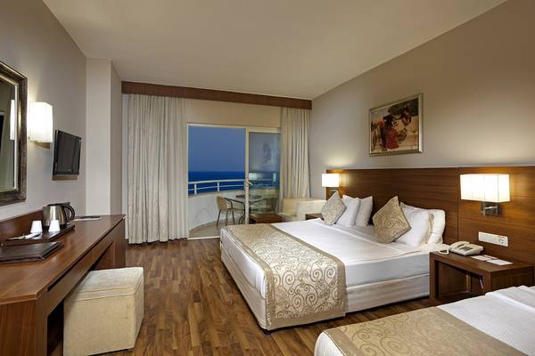 Hotelzimmer mit zwei Betten, Schreibtisch, Aussicht auf das Meer vom Balkon.