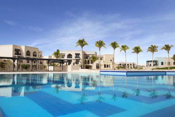 Salalah Rotana Resort Pool mit Palmen und Gebäuden im Hintergrund