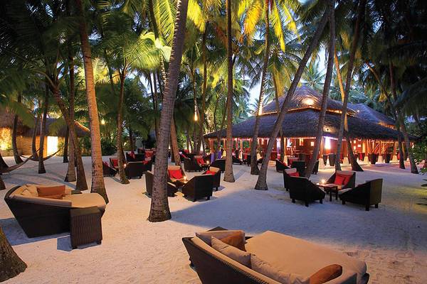 Loungebereich des Baros Maldives Resorts bei Nacht mit Palmen und beleuchteten Gebäuden.