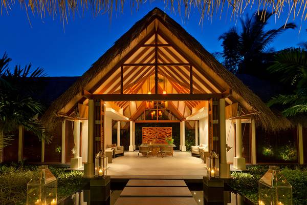 Der Eingang des Baros Maldives Resorts bei Nacht mit beleuchteten Laternen und einem Tisch davor.