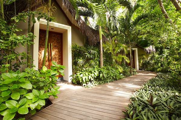 Eingang zum Baros Maldives Resort mit Gehweg durch tropischen Garten