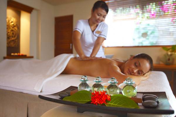 Massage Behandlung im Baros Maldives Resort mit einer Frau, die auf einem Massagetisch liegt.